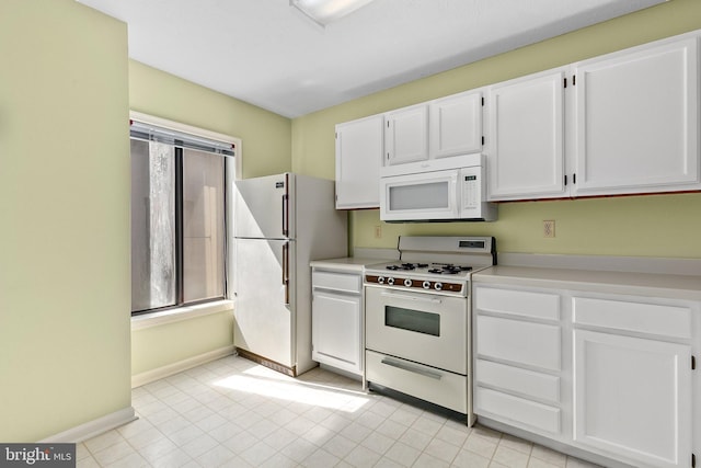 kitchen with white appliances, white cabinets, light countertops, baseboards, and light tile patterned floors