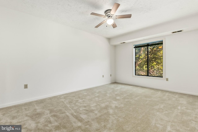empty room featuring carpet flooring, a textured ceiling, ceiling fan, and baseboards
