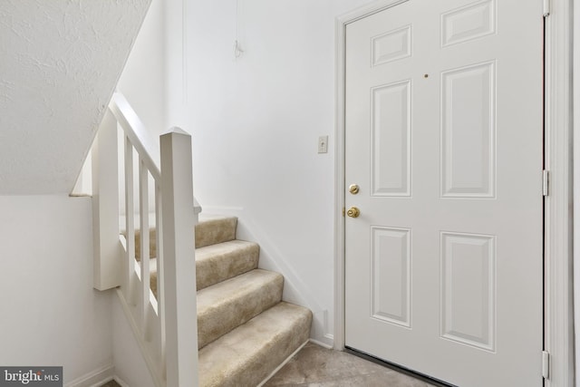 staircase featuring baseboards and carpet flooring