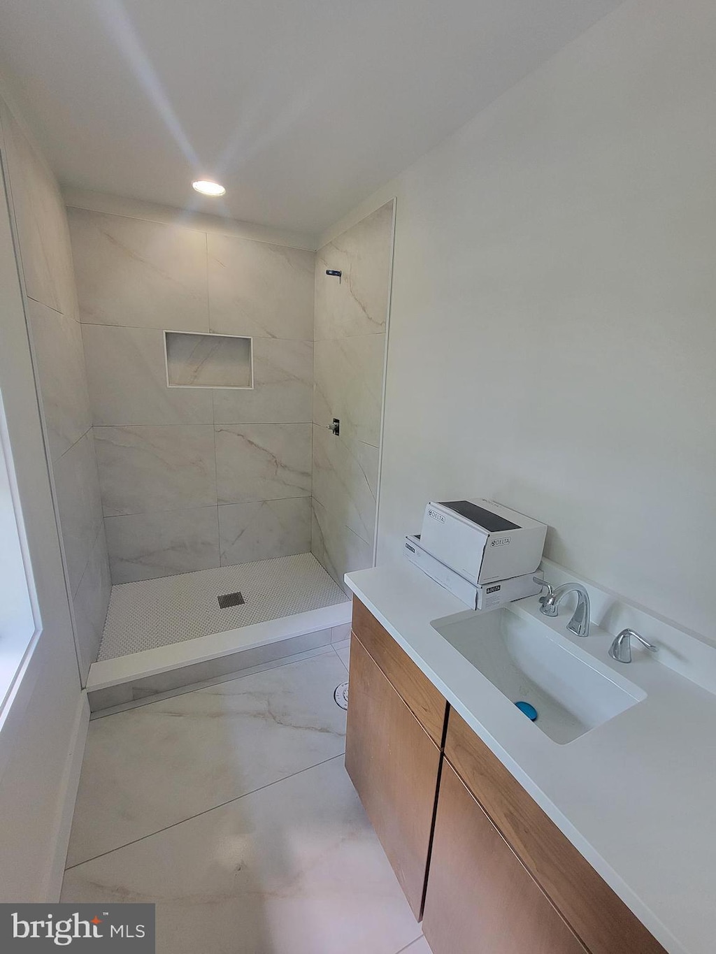 full bath featuring a tile shower and vanity