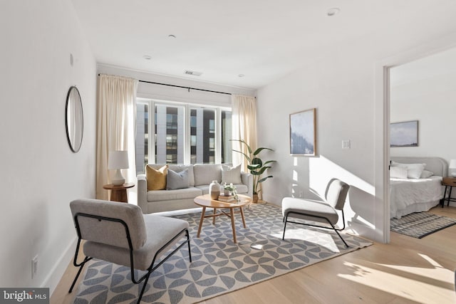 living area with visible vents, wood finished floors, and baseboards