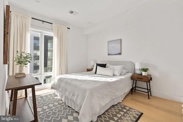bedroom with baseboards, light wood-style floors, and visible vents