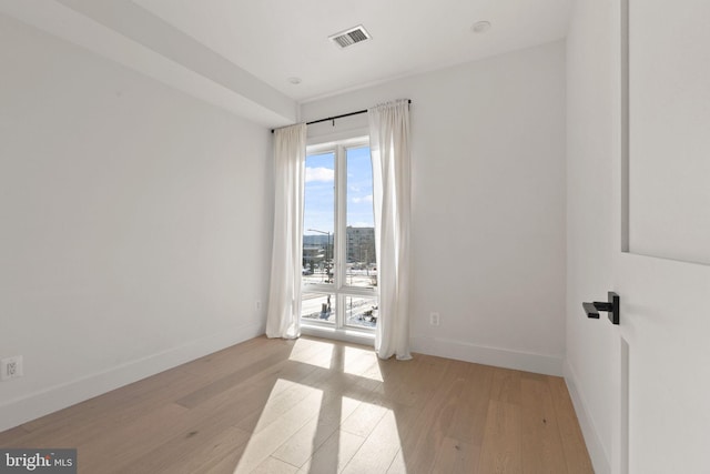 spare room featuring baseboards, visible vents, and light wood-style floors