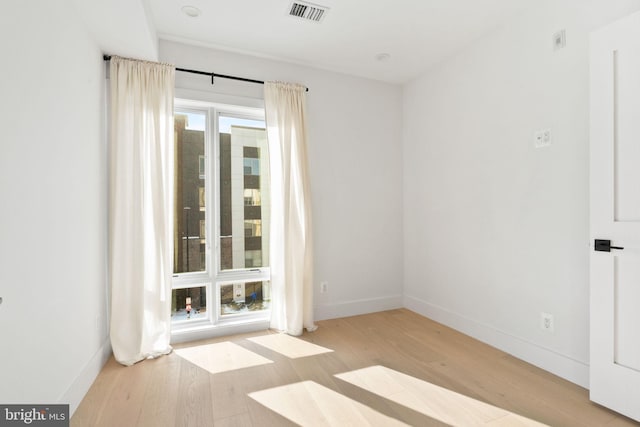 spare room with visible vents, wood finished floors, and baseboards