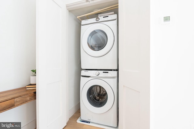 laundry area featuring light wood-type flooring, laundry area, and stacked washer and clothes dryer
