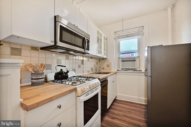 1954 Columbia Rd NW Unit 504, Washington, DC 20009 - kitchen with appliances with stainless steel finishes, dark wood-style flooring, white cabinets, glass insert cabinets, and decorative backsplash