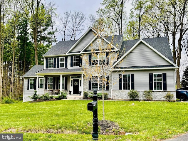 view of front of house featuring covered porch, stone siding, and a front yard
