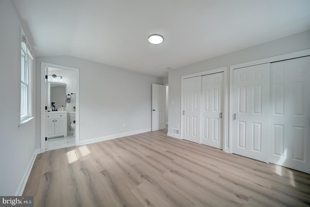 6802 Elbrook Rd, Lanham, MD 20706 - unfurnished bedroom featuring light wood-style flooring, multiple closets, baseboards, ensuite bath, and lofted ceiling