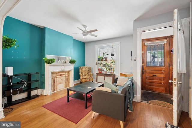 living area featuring a ceiling fan, baseboards, and wood finished floors