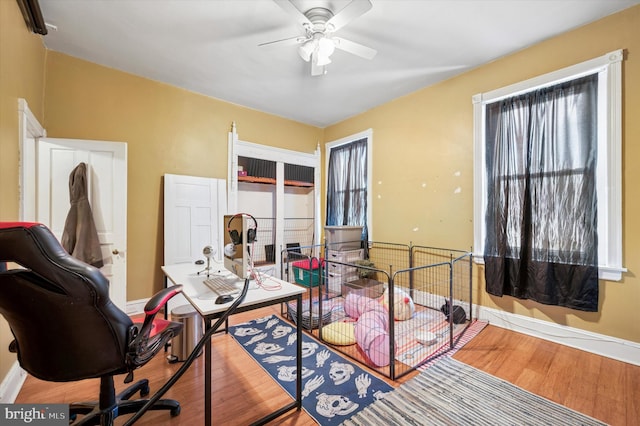 office space featuring wood finished floors, baseboards, and ceiling fan