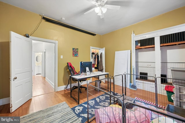 office space featuring baseboards, ceiling fan, and wood finished floors