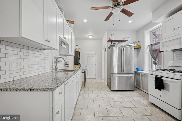kitchen with a sink, white appliances, ceiling fan, white cabinetry, and backsplash
