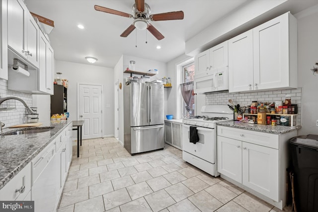kitchen featuring ceiling fan, backsplash, a sink, and white appliances