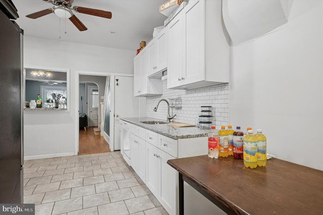 kitchen featuring light stone counters, ceiling fan, a sink, white cabinetry, and tasteful backsplash