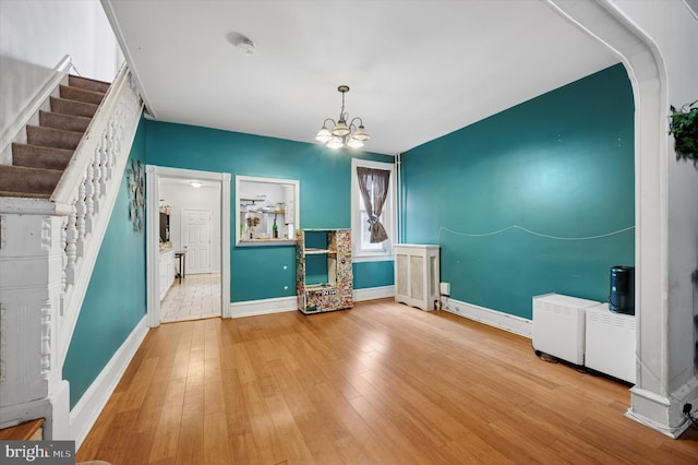 interior space with a chandelier, baseboards, wood-type flooring, and stairway