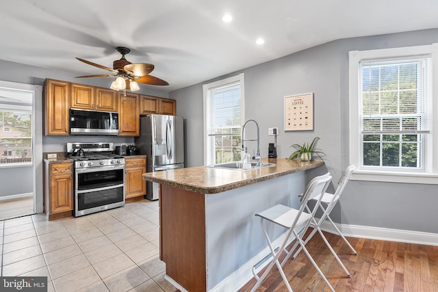 kitchen featuring stainless steel appliances, a sink, healthy amount of natural light, a peninsula, and recessed lighting
