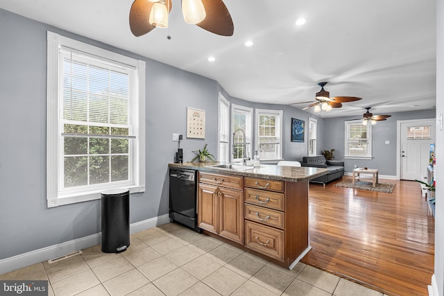 kitchen featuring black dishwasher, a ceiling fan, a peninsula, a sink, and brown cabinets