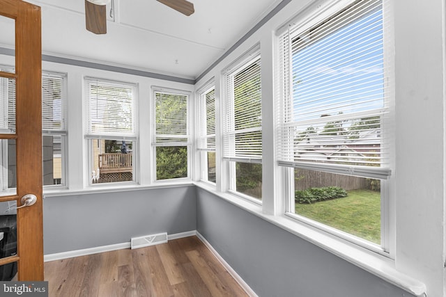 unfurnished sunroom featuring wood finished floors, healthy amount of natural light, and baseboards