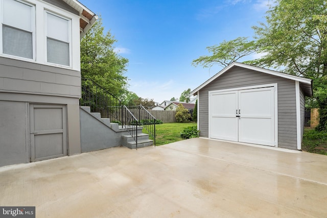 view of patio featuring an outbuilding, stairs, driveway, and a garage