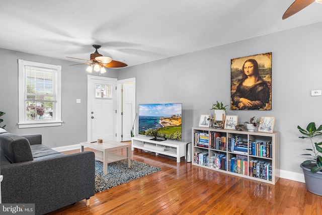living room with a ceiling fan, hardwood / wood-style flooring, and baseboards