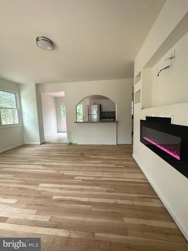 15213 Michigan Rd, Woodbridge, VA 22191 - unfurnished living room featuring a glass covered fireplace, wood finished floors, and plenty of natural light