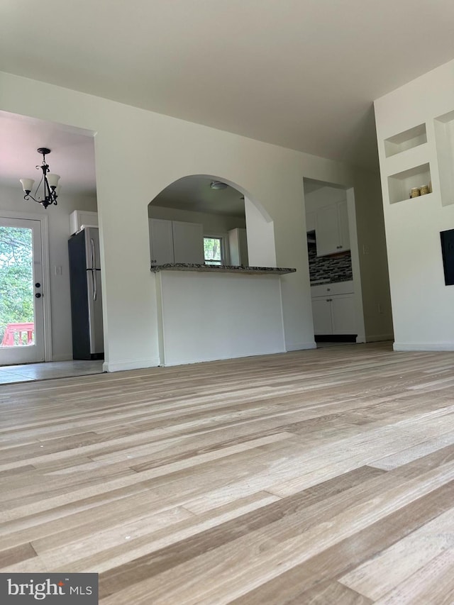 15213 Michigan Rd, Woodbridge, VA 22191 - unfurnished living room with light wood-style floors, a chandelier, and arched walkways