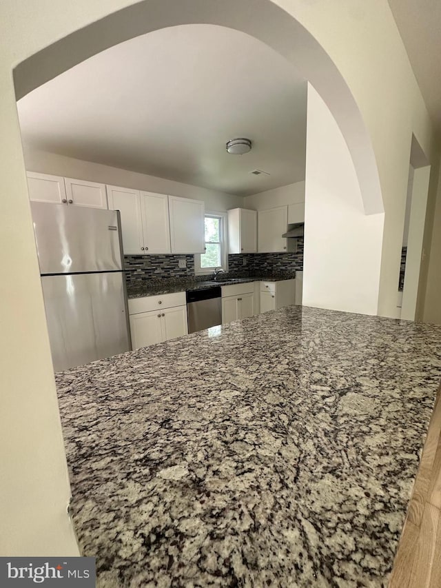 15213 Michigan Rd, Woodbridge, VA 22191 - kitchen featuring appliances with stainless steel finishes, dark stone counters, white cabinetry, and under cabinet range hood