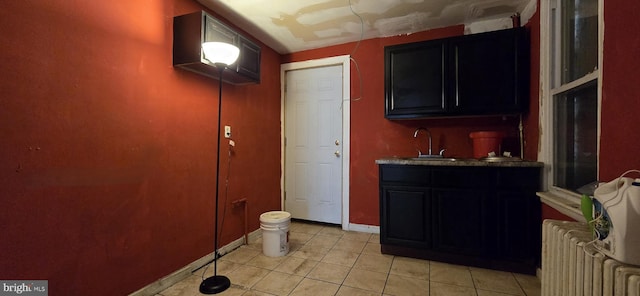 interior space featuring light tile patterned floors, baseboards, a sink, and radiator heating unit