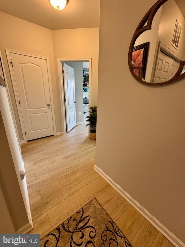 corridor featuring light wood-style flooring and baseboards