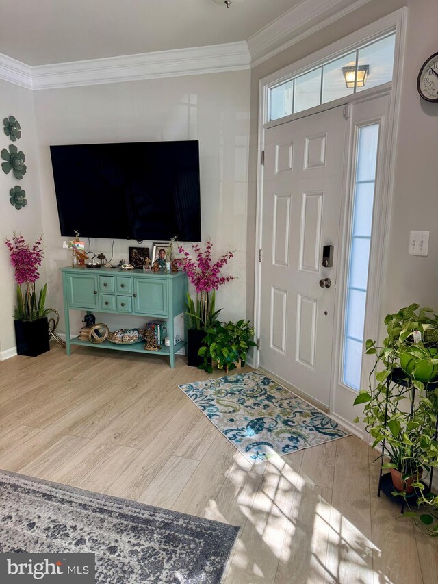 foyer featuring wood finished floors, crown molding, and baseboards