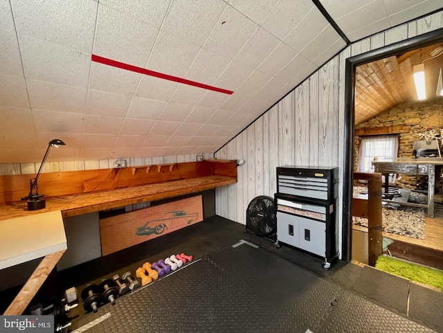 bonus room featuring lofted ceiling and wooden walls