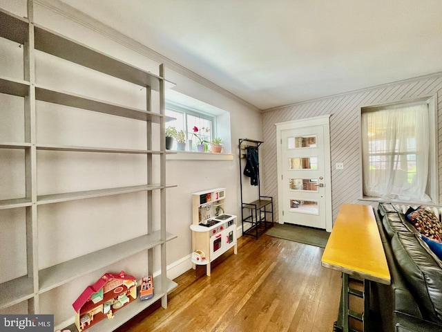 interior space with wood finished floors, ornamental molding, and baseboards
