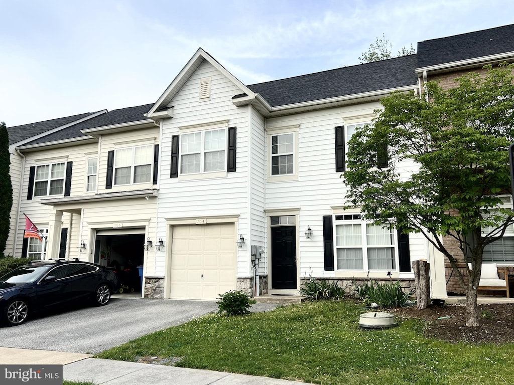 multi unit property featuring stone siding, driveway, a garage, and a front yard