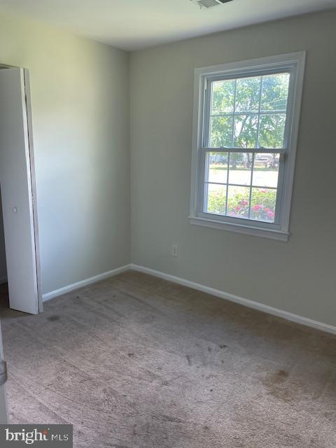 carpeted empty room featuring baseboards