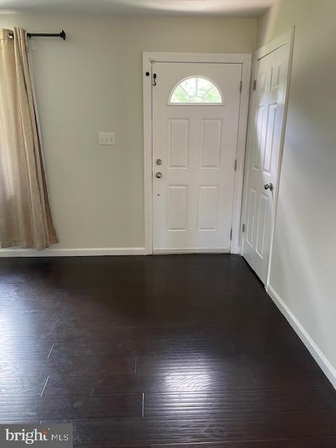 entrance foyer with dark wood-type flooring and baseboards