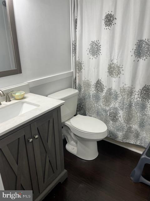 bathroom featuring wood finished floors, vanity, toilet, and a shower with curtain
