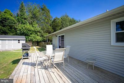 wooden deck featuring a yard, outdoor dining area, an outdoor structure, and a storage unit