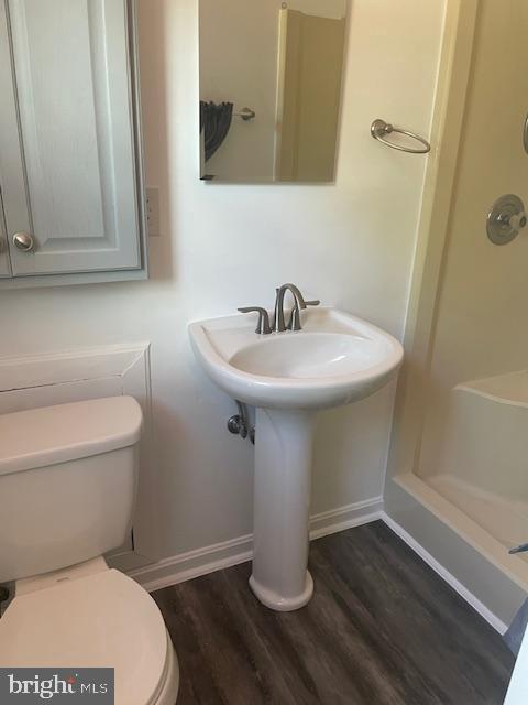full bath with wood finished floors, toilet, a shower, and baseboards