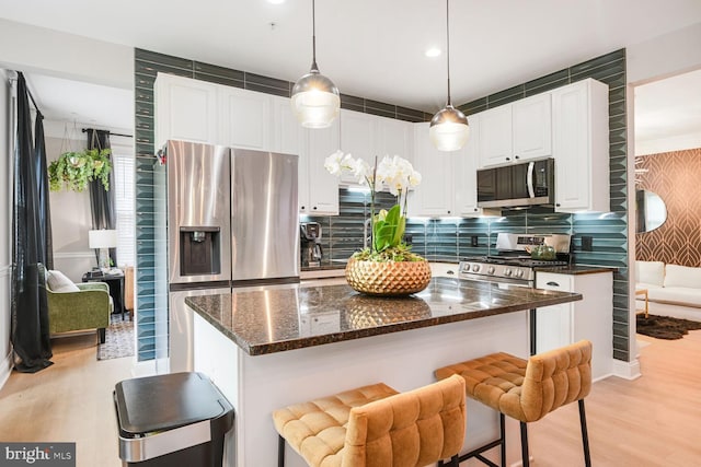 502 King Farm Blvd Unit 202, Rockville, MD 20850 - kitchen with a center island, light wood-style flooring, stainless steel appliances, white cabinets, and backsplash