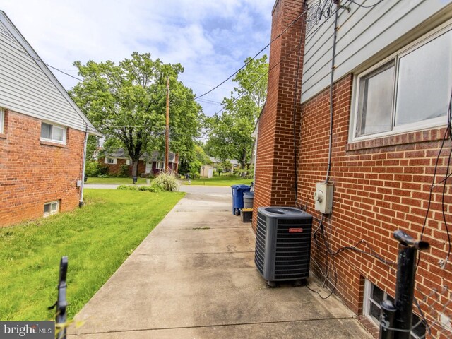 6215 Seminole Pl, College Park, MD 20740 - view of property exterior featuring central air condition unit, a lawn, brick siding, a patio, and a chimney