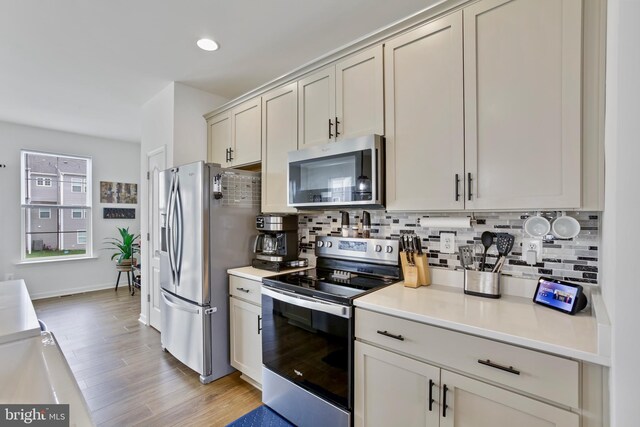 kitchen with stainless steel appliances, decorative backsplash, light countertops, light wood-style floors, and recessed lighting