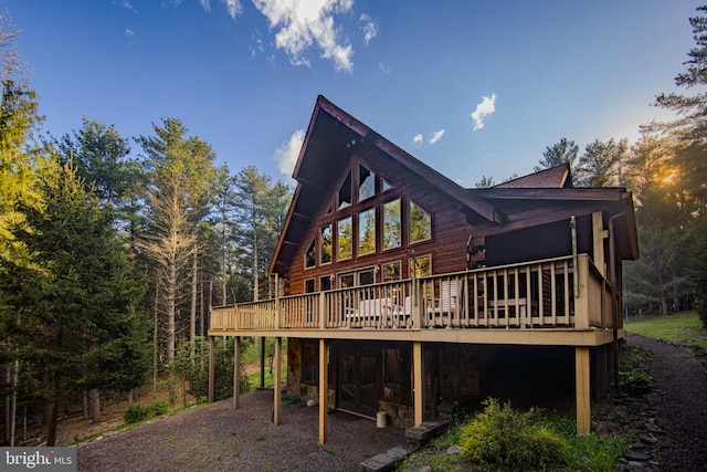 back of property with a deck, stone siding, and log siding
