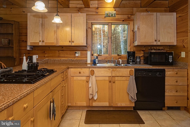 kitchen with a sink, wooden walls, light brown cabinets, and black appliances
