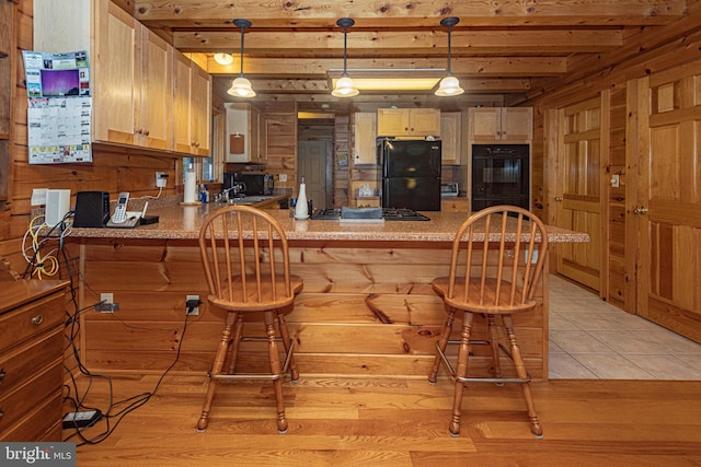 kitchen with black appliances, a kitchen breakfast bar, a peninsula, and decorative light fixtures