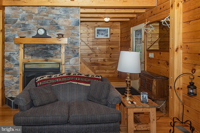 living area with beamed ceiling, wood walls, a fireplace, and wood finished floors