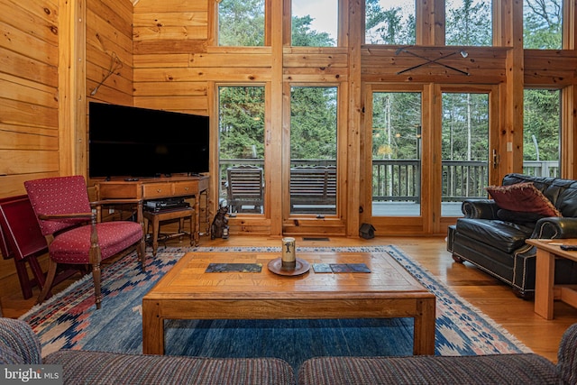 living area featuring wooden walls, a towering ceiling, and wood finished floors
