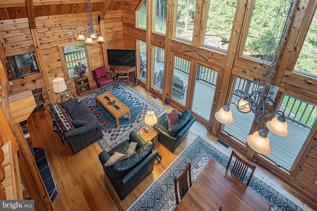 living room featuring beam ceiling, wood finished floors, an inviting chandelier, wooden walls, and wood ceiling