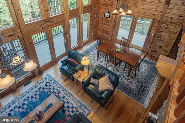 dining area featuring wooden walls, a notable chandelier, visible vents, and wood finished floors
