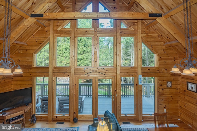 interior space with high vaulted ceiling, wooden walls, and a notable chandelier