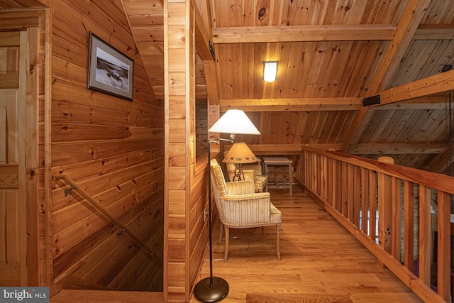sitting room featuring wooden ceiling, wood walls, light wood-type flooring, and vaulted ceiling with beams
